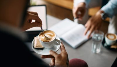 Close up of entrepreneur having cup of coffee during business meeting in cafe.
